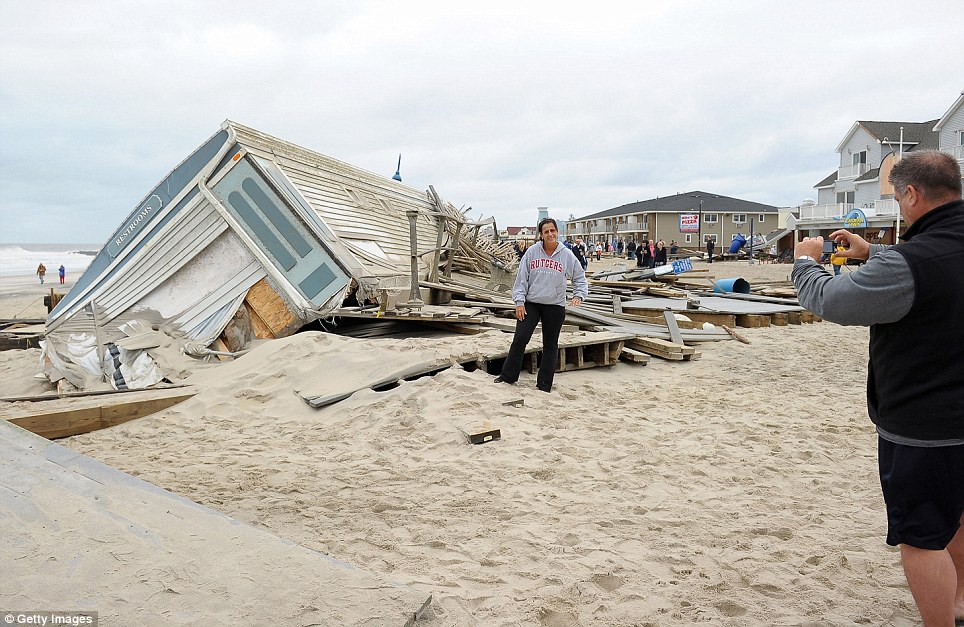 Snap: A man takes a picture of a woman in front of a crumbled public bathroom following Superstorm Sandy, on Tuesday in Belmar, New Jersey